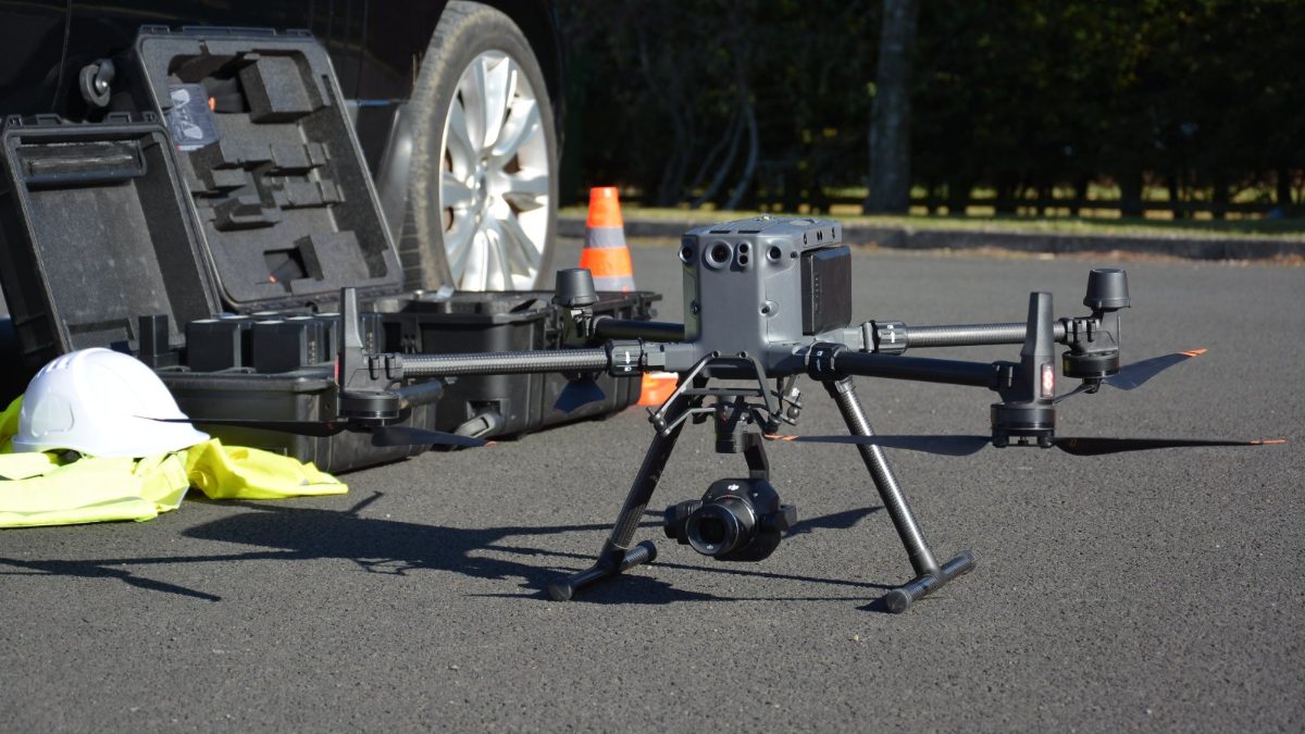 DJI Matrice 350 RTK drone with a Zenmuse P1 camera, set up on tarmac beside an open equipment case, with a hard hat, a high-visibility vest and a traffic cone