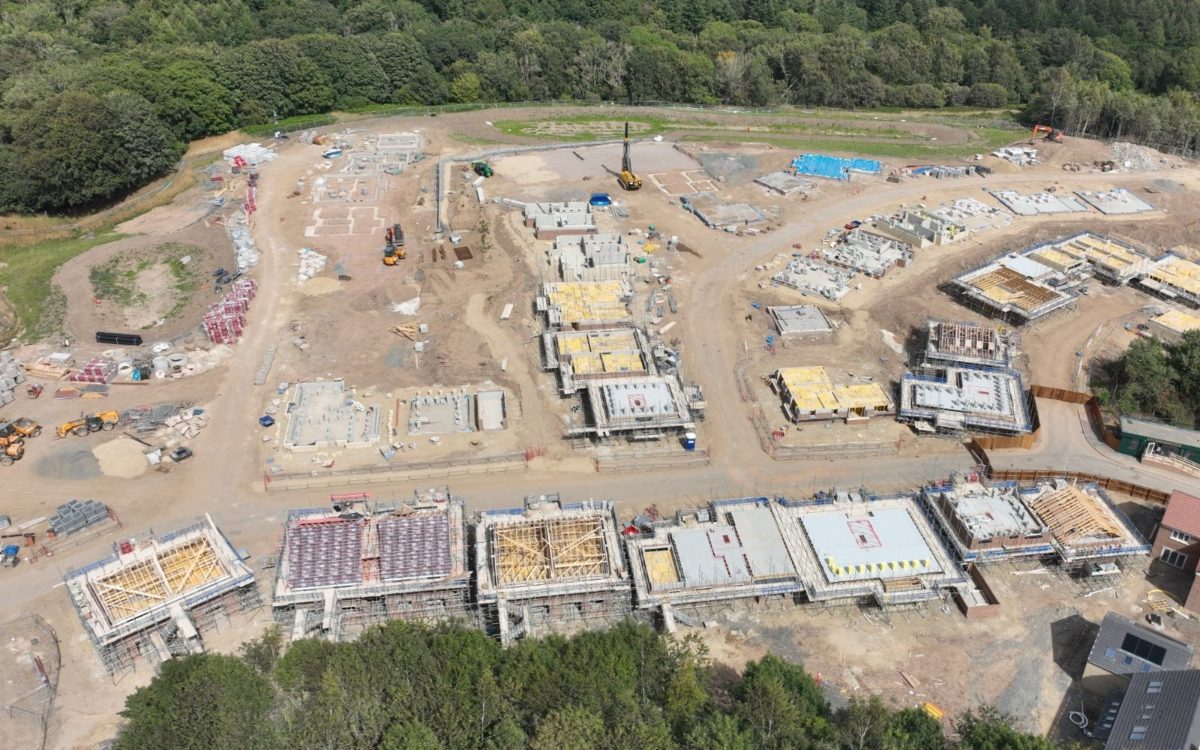 Aerial view of a housing development at an earlier stage: foundation slabs, blockwork and timber roof trusses under construction