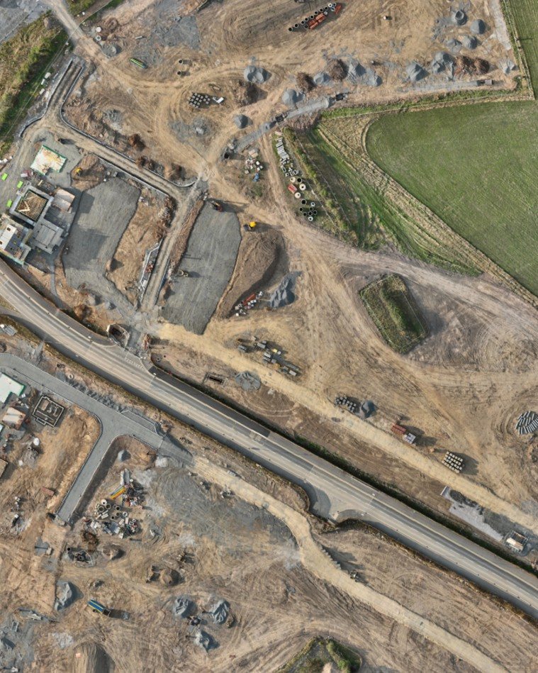 Orthomosaic of a housing development at an earlier stage: earthworks, stockpiles and the first foundations either side of the spine road